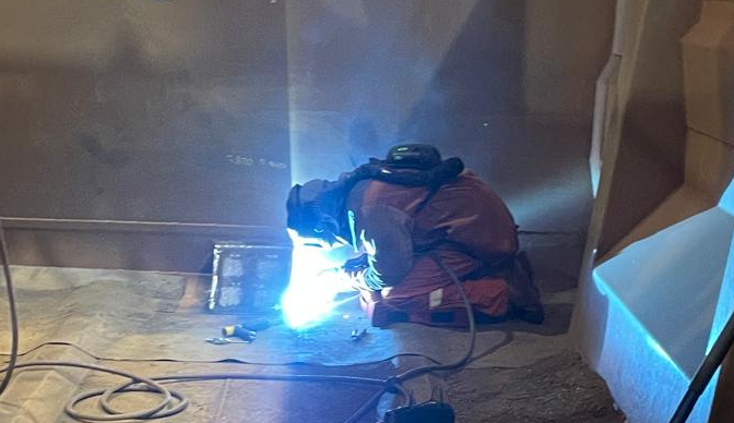Welder making repairs inside a rail wagon